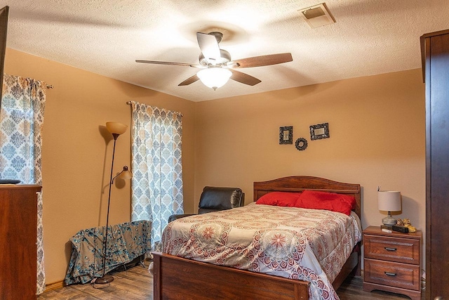 bedroom with ceiling fan, wood-type flooring, and a textured ceiling