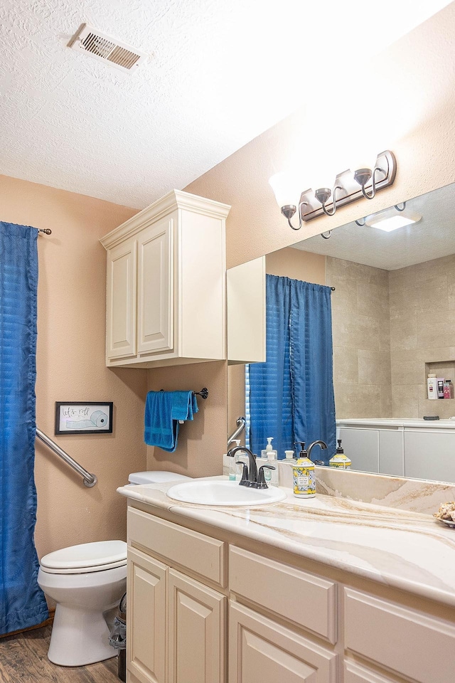 bathroom featuring wood-type flooring, vanity, a textured ceiling, and toilet