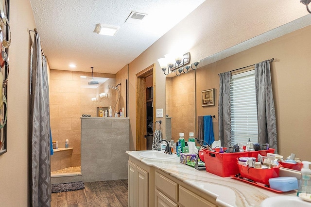 bathroom with tiled shower, vanity, a textured ceiling, and hardwood / wood-style flooring