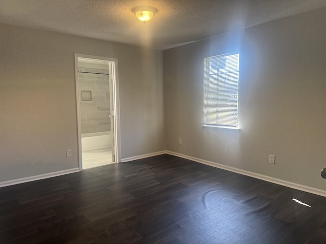 spare room with a textured ceiling and dark hardwood / wood-style floors