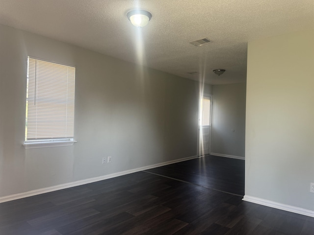 unfurnished room with dark wood-type flooring and a textured ceiling