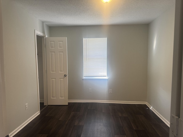 spare room with a textured ceiling and dark hardwood / wood-style flooring