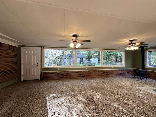 interior space featuring ceiling fan and brick wall