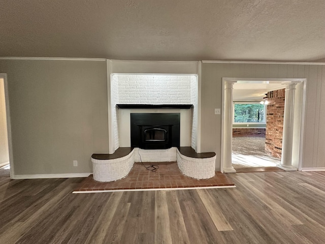 unfurnished living room featuring hardwood / wood-style floors, ornamental molding, a textured ceiling, and decorative columns