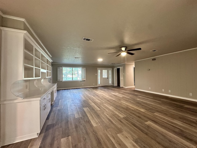 unfurnished living room with a textured ceiling, dark hardwood / wood-style floors, ceiling fan, and ornamental molding