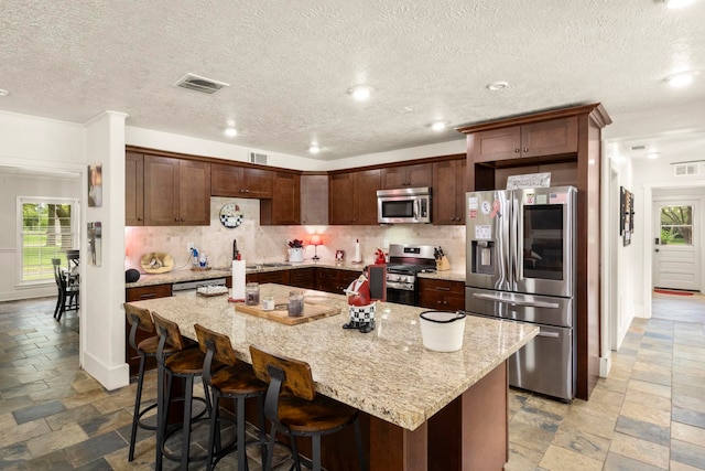1280 Cherokee Ln, Beaumont, TX 77702 - kitchen featuring appliances with stainless steel finishes, stone tile floors, backsplash, a kitchen island, and recessed lighting
