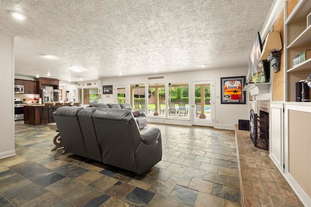 1280 Cherokee Ln, Beaumont, TX 77702 - living area with stone tile flooring, a textured ceiling, a brick fireplace, and recessed lighting