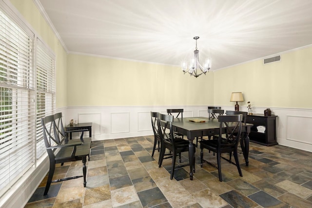 1280 Cherokee Ln, Beaumont, TX 77702 - dining room featuring a chandelier, dark stone finish flooring, crown molding, a wainscoted wall, and a decorative wall
