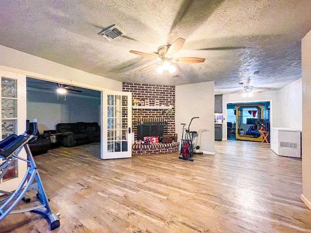 workout room with a fireplace, hardwood / wood-style floors, a textured ceiling, and french doors