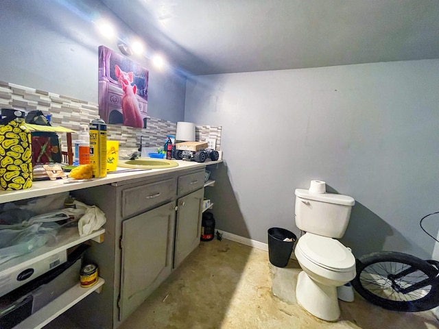 bathroom featuring tasteful backsplash, vanity, concrete floors, and toilet