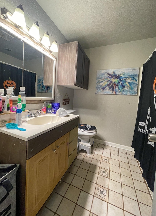 bathroom with tile patterned flooring, vanity, a textured ceiling, and toilet