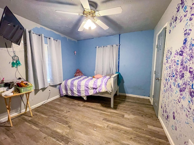 bedroom with hardwood / wood-style flooring, ceiling fan, and a textured ceiling