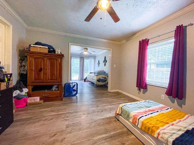 bedroom featuring hardwood / wood-style flooring, ceiling fan, crown molding, and multiple windows