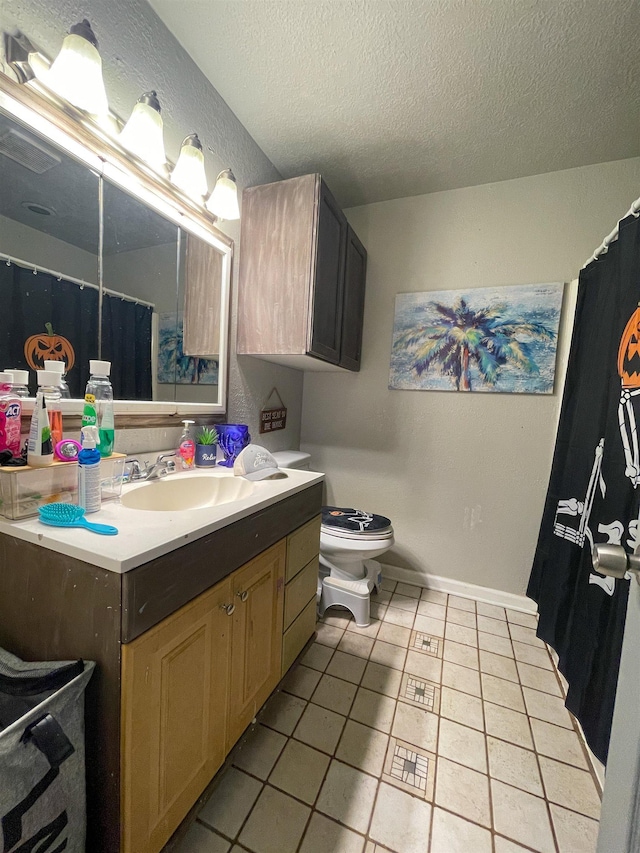 bathroom with tile patterned floors, vanity, a textured ceiling, and toilet