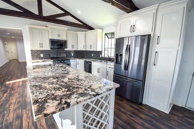 kitchen with backsplash, vaulted ceiling with beams, light stone counters, appliances with stainless steel finishes, and a sink