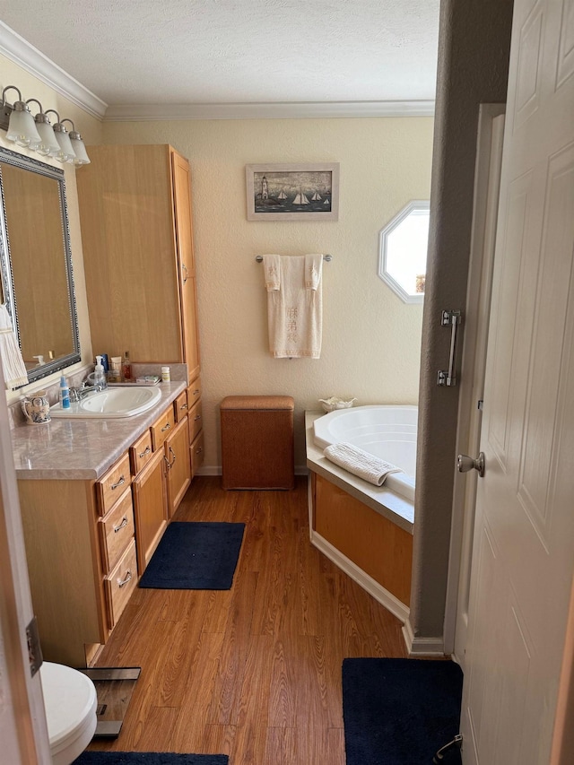 bathroom featuring a tub to relax in, ornamental molding, vanity, hardwood / wood-style floors, and toilet