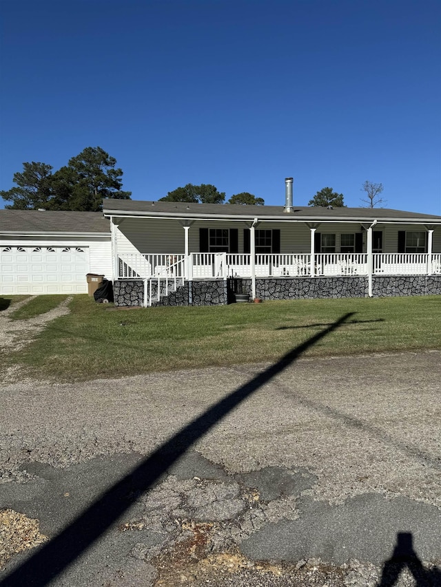 view of front of home with covered porch, a garage, and a front lawn