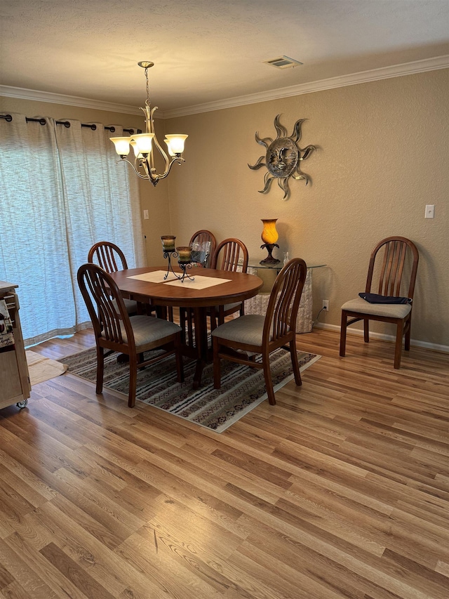 dining room featuring hardwood / wood-style flooring, crown molding, and a notable chandelier