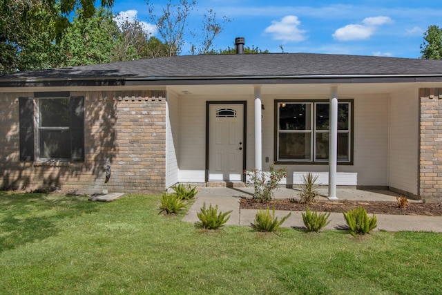 view of exterior entry with a lawn and a porch