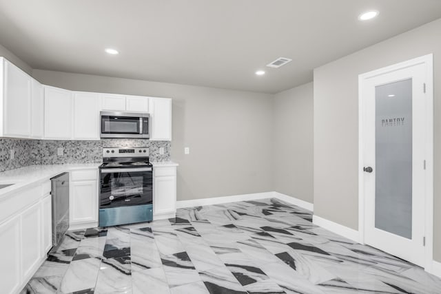 kitchen featuring decorative backsplash, white cabinets, and appliances with stainless steel finishes