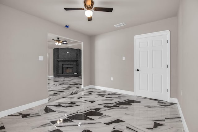 interior space with ceiling fan and a brick fireplace