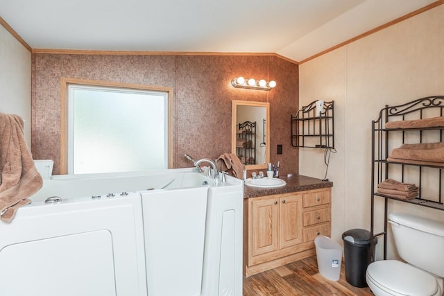 bathroom featuring vanity, vaulted ceiling, ornamental molding, wood-type flooring, and washer / clothes dryer