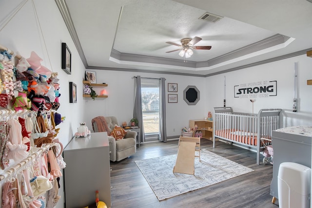 bedroom with dark hardwood / wood-style floors, a tray ceiling, a textured ceiling, and crown molding