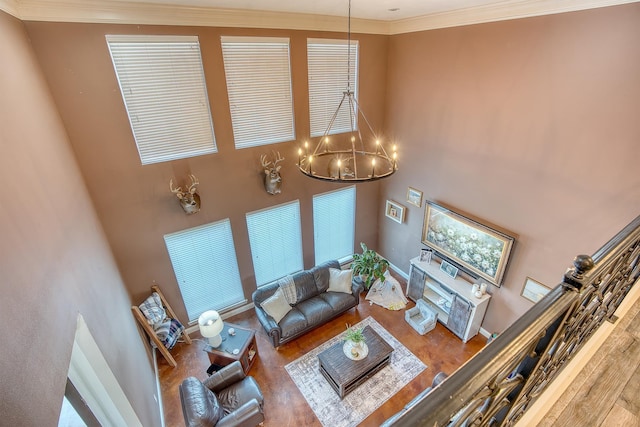 living room featuring hardwood / wood-style floors, crown molding, a chandelier, and a high ceiling