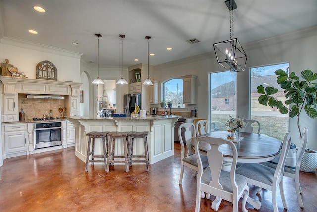 kitchen with stainless steel appliances, a kitchen island, hanging light fixtures, and concrete floors