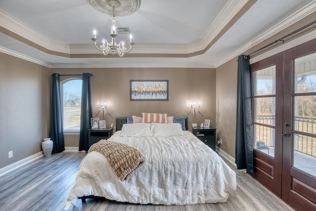 bedroom with french doors, a tray ceiling, hardwood / wood-style floors, and crown molding