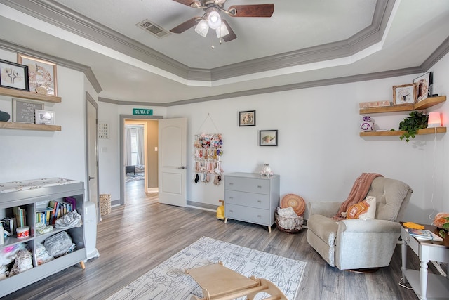 sitting room featuring crown molding, hardwood / wood-style flooring, a raised ceiling, and ceiling fan