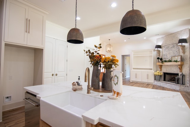 kitchen with pendant lighting, light stone counters, and sink