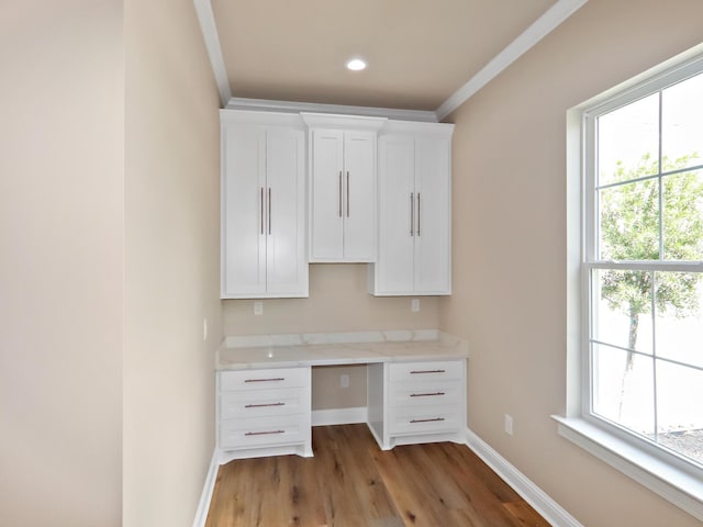 unfurnished office featuring recessed lighting, baseboards, built in study area, light wood finished floors, and crown molding