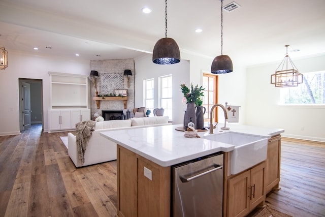 kitchen with appliances with stainless steel finishes, pendant lighting, a center island with sink, light hardwood / wood-style flooring, and a breakfast bar area