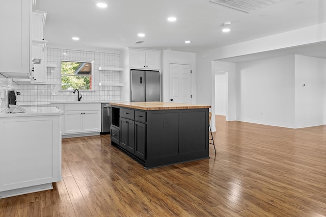 kitchen featuring wood finished floors, white cabinets, wood counters, and stainless steel refrigerator