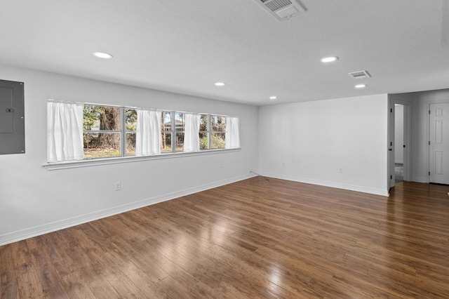 empty room featuring wood finished floors, visible vents, and a healthy amount of sunlight