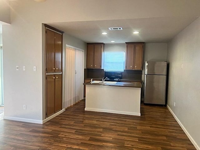 kitchen featuring dark wood-type flooring, freestanding refrigerator, dark countertops, and baseboards