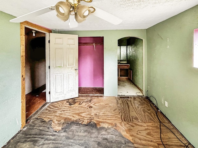 unfurnished bedroom featuring ceiling fan, a textured ceiling, and a closet