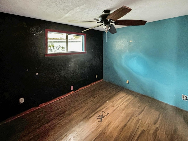 spare room featuring ceiling fan, wood-type flooring, and a textured ceiling