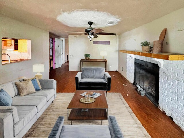 living room with ceiling fan, wood-type flooring, and a textured ceiling