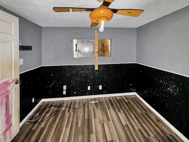 unfurnished dining area featuring ceiling fan, wood-type flooring, and a textured ceiling