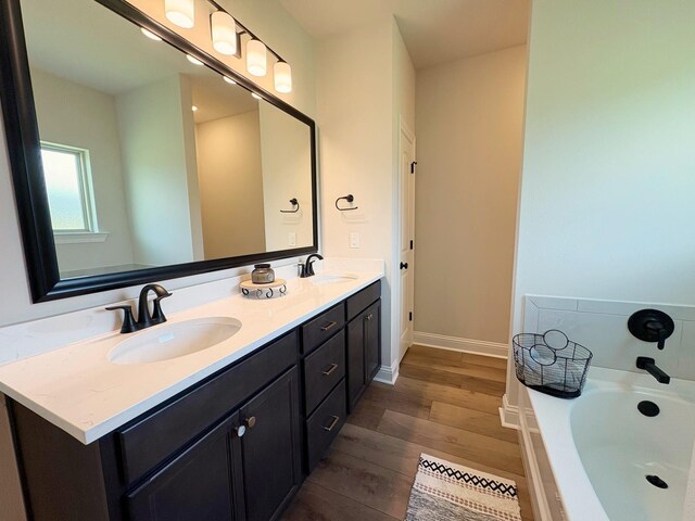 1240 Little Cypress Loop, Orange, TX 77632 - bathroom featuring wood finished floors, a bath, double vanity, and baseboards