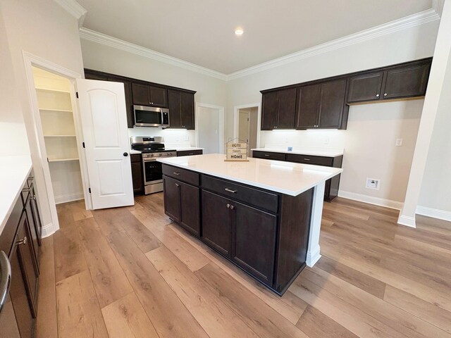 1240 Little Cypress Loop, Orange, TX 77632 - kitchen with appliances with stainless steel finishes, crown molding, light wood-style flooring, a kitchen island, and dark brown cabinetry