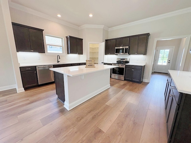 1240 Little Cypress Loop, Orange, TX 77632 - kitchen featuring appliances with stainless steel finishes, a sink, crown molding, a center island, and light wood-style floors
