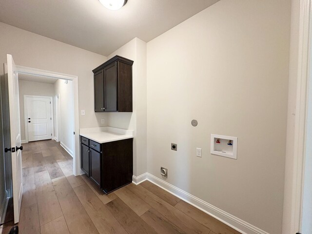 1240 Little Cypress Loop, Orange, TX 77632 - clothes washing area featuring electric dryer hookup, hookup for a washing machine, light wood-style floors, and cabinet space