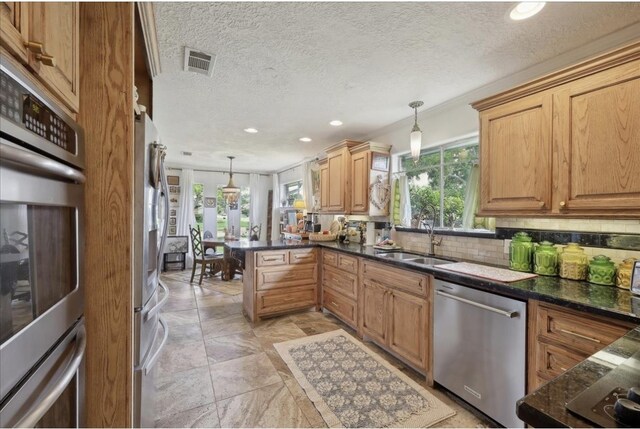 kitchen featuring visible vents, recessed lighting, a sink, decorative light fixtures, and stainless steel appliances