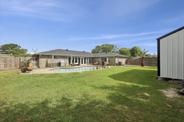 rear view of property with a yard, brick siding, a fenced in pool, and a fenced backyard