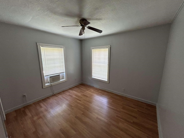 spare room featuring ceiling fan, cooling unit, wood-type flooring, and a textured ceiling