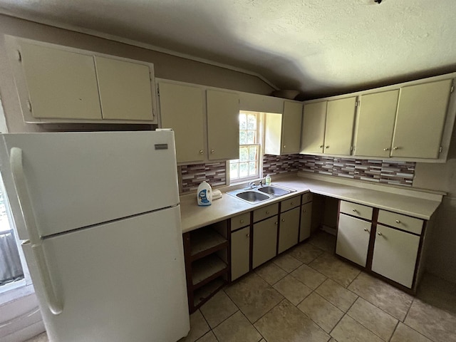 kitchen featuring white refrigerator, sink, vaulted ceiling, tasteful backsplash, and light tile patterned flooring