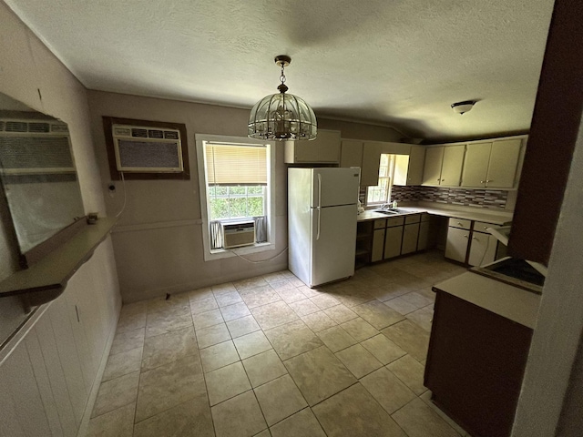 kitchen featuring tasteful backsplash, a wall unit AC, white refrigerator, decorative light fixtures, and a chandelier